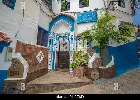 Typique, vieux, brown, finement sculptés, porte cloutée riad marocain et porte cadre et maison ancienne. bleu ville dans la médina de Chefchaouen, Maroc Banque D'Images