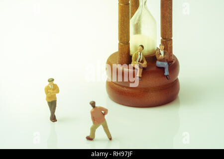 Avis de jouet miniature personnes avec hourglass vintage sur fond blanc. Vintage style. Banque D'Images