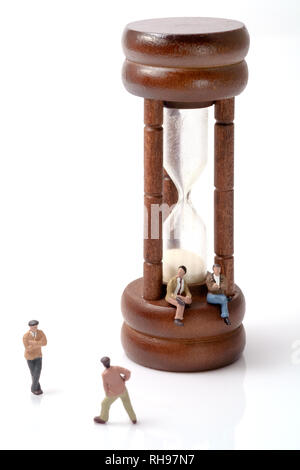 Avis de jouet miniature personnes avec hourglass vintage sur fond blanc. Banque D'Images