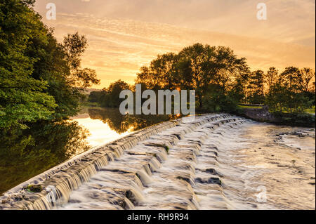 Scenic de soleil colorés sky over rural landscape (l'eau qui coule doucement vers le bas) - étapes Weir River Wharfe, Burley dans Wharfedale, Yorkshire, Angleterre, Royaume-Uni. Banque D'Images