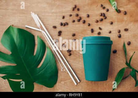 Eco réutilisables élégant tasse à café et en acier avec une paille sur fond de bois et de feuilles de bambou vert monstera, télévision lay. En plastique à usage unique interdiction Banque D'Images
