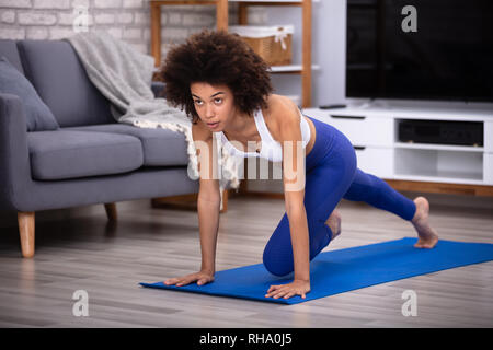 Certains jeunes femmes athlètes dans l'exercice de Fitness Sportswear sur le tapis à la maison Banque D'Images