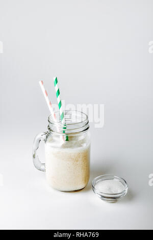 Un verre de protéine avec la vanille et la poudre sur un fond blanc Banque D'Images