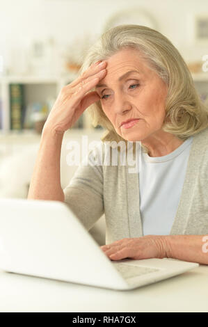 Senior woman sitting at table with laptop Banque D'Images
