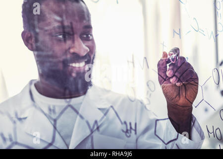 Les jeunes habile assistant chimique debout près du verre Banque D'Images