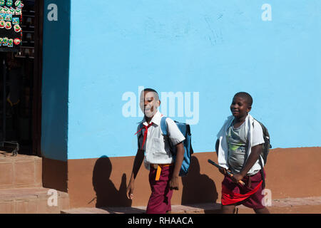 Deux collégiens à pied sur th Street à Cuba Trinidad. Smiling boys sur fond bleu mur. Les enfants ont des pionniers rouge. Banque D'Images