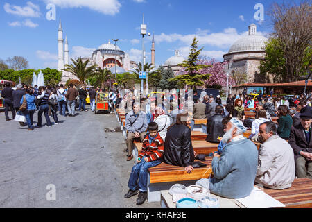 Istanbul, Turquie : Les gens s'assoient sur la place Sultanahmet avec Sainte-sophie en arrière-plan. Banque D'Images