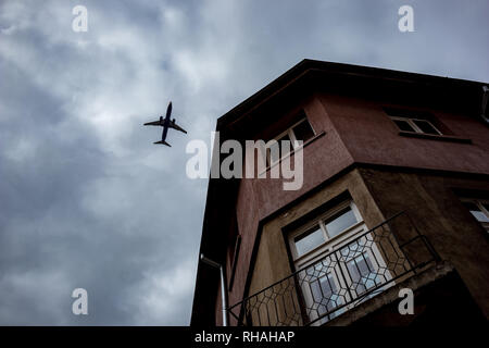 Airplane silhouette sur le fond bleu-blanc de l'automne nuageux ciel en soirée et deux étages chambre avec petit balcon vide à Sofia, Bulgarie Banque D'Images