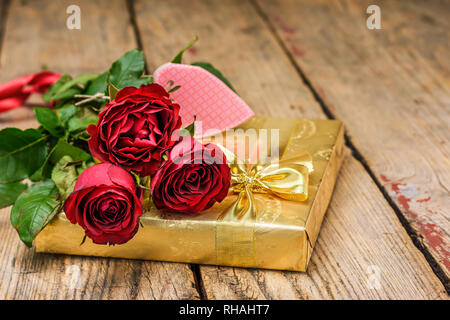 Roses rouges et boîte-cadeau doré sur fond sombre. La Saint-Valentin et Mother's Day card concept. Banque D'Images