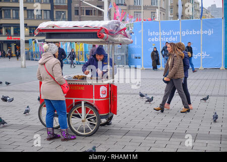 L'achat d'une femme marron les vendeurs de rue panier sur une froide journée d'hiver. Sur la place Taksim, avec les spectateurs. Istanbul, Turquie Banque D'Images