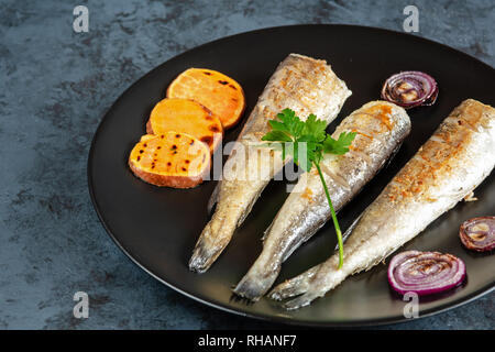 Merlu frit servi avec patates douces et oignons rouges. Banque D'Images