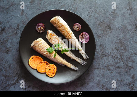 Merlu frit servi avec patates douces et oignons rouges. Banque D'Images