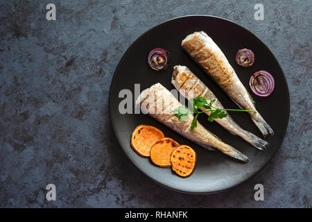 Merlu frit servi avec patates douces et oignons rouges. Banque D'Images