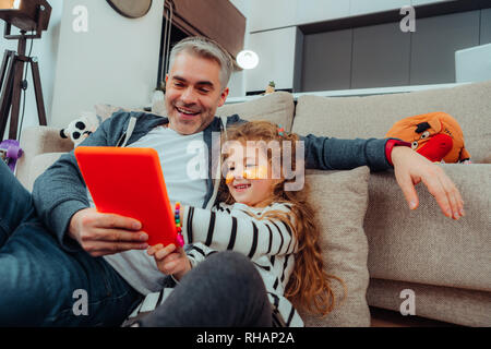 Adorable petite fille rousse avec un bracelet lumineux et son père de se sentir bien Banque D'Images