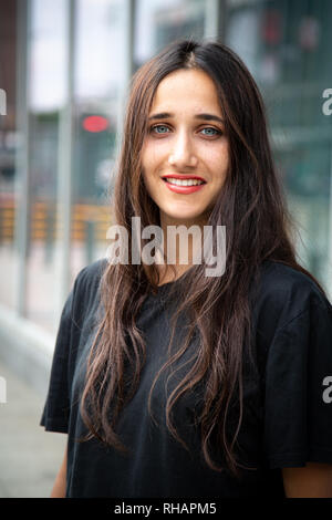 Belle jeune femme à la peau d'olive avec les yeux de couleur claire à l'extérieur permanent en milieu urbain. Banque D'Images