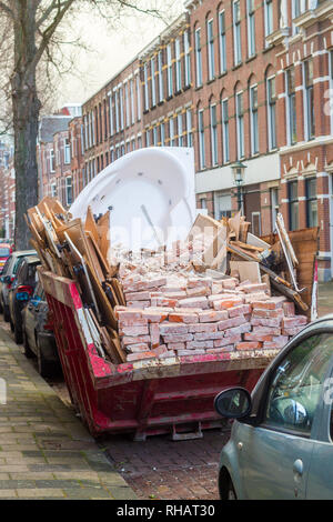 La Haye, Pays-Bas - le 28 juin 2019 : rubbish skip plein de briques, jacuzzi bain à remous et de bois sur rue bondée Banque D'Images