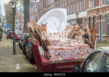 La Haye, Pays-Bas - le 28 juin 2019 : rubbish skip plein de briques, jacuzzi bain à remous et de bois sur rue bondée Banque D'Images