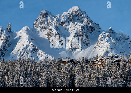 Chalets nichés dans les arbres, dans la station de ski alpin de Courchevel avec le sommet de la Saulire derrière. Courchevel 1850. Banque D'Images