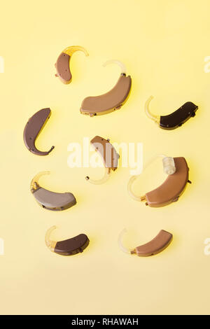 Un vieux appareils auditifs analogiques sur fond jaune, alternative à la chirurgie. Accessoire d'ENT Banque D'Images