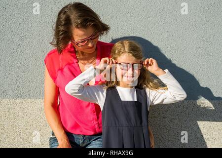 Maman et sa petite fille, un étudiant, profitez de la socialisation. La jeune fille sourit et ajuste ses lunettes. Retour à l'école ! Banque D'Images