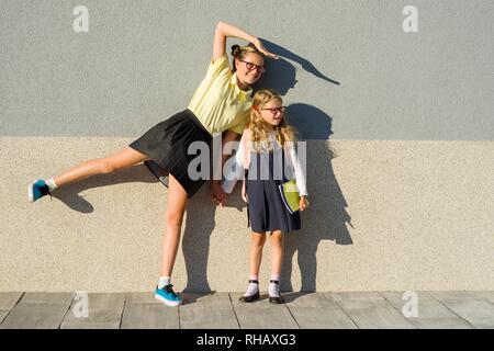 Portrait plein air de deux filles. Un élève du secondaire et une école primaire se font passer pour un appareil photo. Banque D'Images