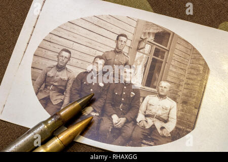 Carte photo de 5 soldats lettons en période autour de 1935 et de balles de fusil sur trench coat à l'arrière-plan Banque D'Images