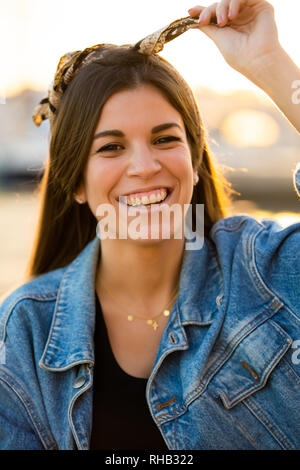 Jeune femme souriante avec ses cheveux attachés avec un bandana Banque D'Images