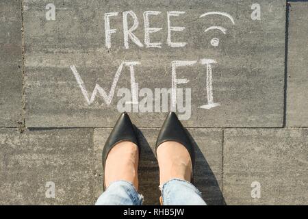 Pieds femelles avec texte wi fi écrit sur trottoir gris Banque D'Images