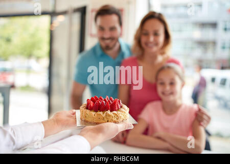 Gâteau fraises Sweet girl avec les parents en confiserie Banque D'Images