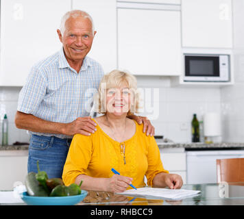 Portrait of mature couple à table de cuisine du remplissage des documents Banque D'Images