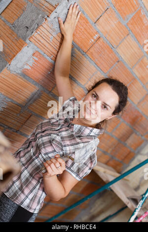 Une femme habile engagés dans des travaux de rénovation à l'intérieur, travaillant avec une truelle de plâtrage Banque D'Images