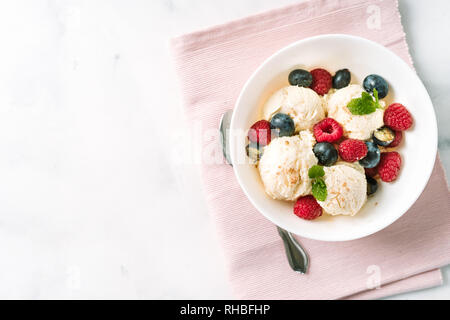 Vue de dessus de la crème de glace à la vanille aux fruits rouges dans un bol sur serviette rose Banque D'Images