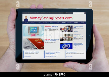 Un homme regarde le MoneySavingExpert site sur son iPad tablet device, tourné contre une table en bois page contexte (usage éditorial uniquement). Banque D'Images