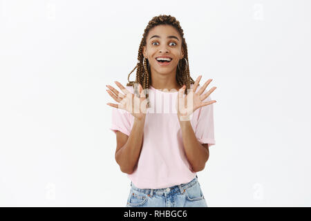 Fasciné et excité surpris talktive sortant, femme à la peau sombre attrayant avec dreads gesticulant avec rased palmiers et tout sourire à la Banque D'Images