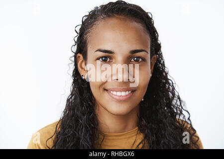 Portrait de jeune timide et friendly happy african-american femme avec de longs cheveux bouclés smiling at camera joyeusement à heureux et optimiste que Banque D'Images