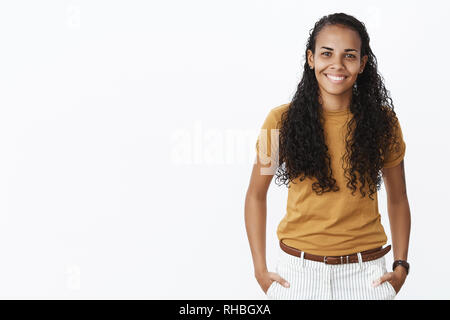 Tourné à l'intérieur de l'assurance-amical à la femme africains-américains d'aider un collègue newbie dans office holding hands in pockets en souriant joyeusement à Banque D'Images