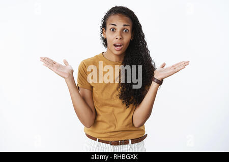 Studio shot of freak out african-petite amie américaine article choqués et sans voix comme étant mis en doute et confusion, ne peut pas comprendre ce qui s'est passé Banque D'Images