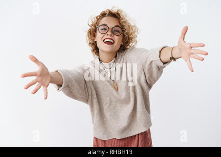 Fille veut des caresses. Portrait de heureux et enthousiaste de charme féminin européen attrayant avec de courts cheveux blonds dans les verres et les mains pour étirer chandail Banque D'Images