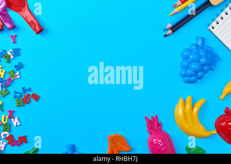 Fond bleu avec des jouets en plastique pour enfants, des crayons, des ballons et des lettres de l'alphabet anglais, l'espace vide Banque D'Images