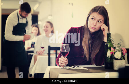 Femme élégante en colère s'attend à ce que l'homme pour le dîner dans le restaurant de luxe intérieur. Banque D'Images