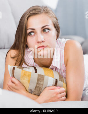 Portrait de sad young woman lying on sofa coussin Banque D'Images