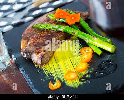 Partie de moyennes et Pavé de boeuf aux asperges et sauce verte sur la plaque noire Banque D'Images