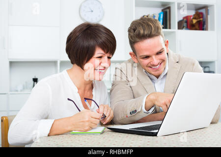Heureuse maman et fils d'examiner de nouveaux logiciels sur laptop sitting at table Banque D'Images