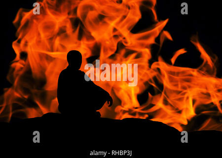 Silhouette d'un moine, méditant sur fond d'incendie Banque D'Images
