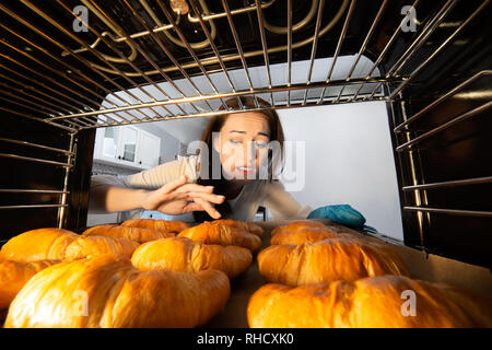 Worried Woman Contrôle Croissants frais avec son doigt au four Banque D'Images