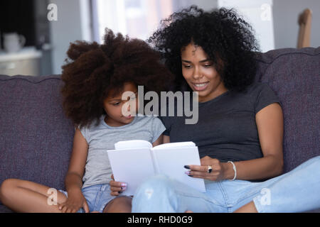 African American maman lecture livre à ma petite fille à la maison Banque D'Images