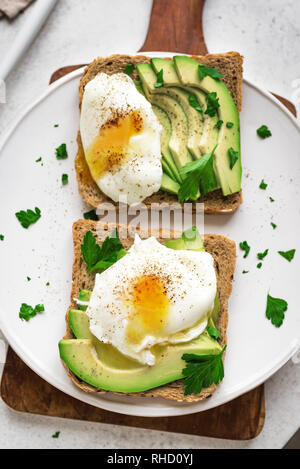 L'avocat des sandwichs avec les oeufs pochés - tranches d'avocat et d'œufs sur du pain grillé pour le petit déjeuner ou une collation saine. Banque D'Images