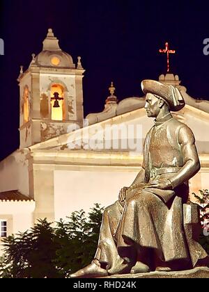 Vue nocturne de la sculpture d'Henrique à Lagos avec l'église située à la côte de l'algarve du Portugal Banque D'Images