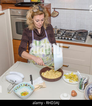 Femme au foyer concentré en versant une pâte de desserts aux pommes dans le moule Banque D'Images