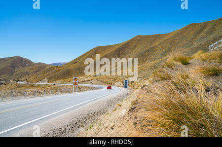 Lindis Pass paysage de collines couvertes de touffes d'or sous ciel bleu. Banque D'Images